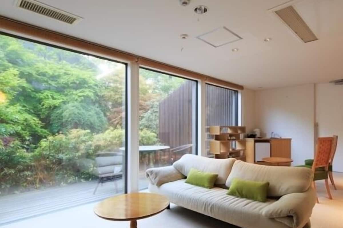 A modern living room with a sofa, a small round table, and a view of greenery outside.