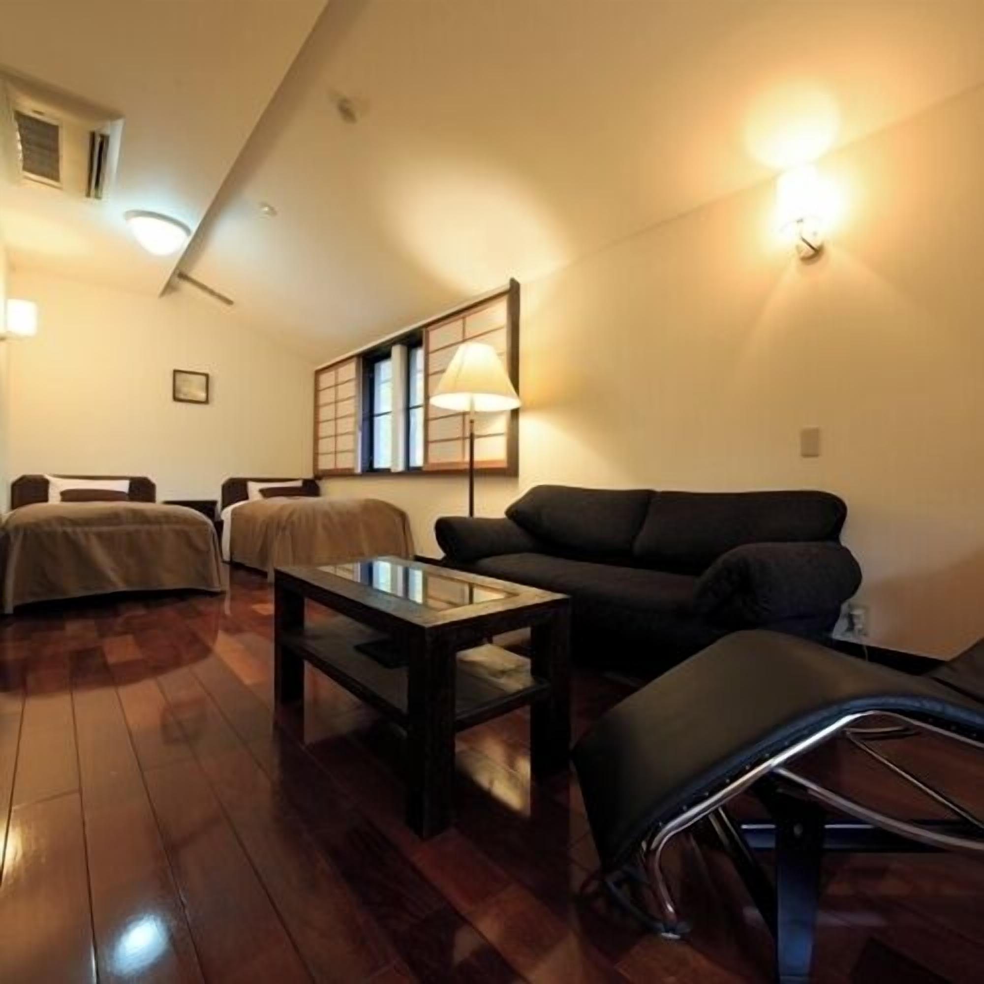 Una habitación con cama, sofá, mesa y lámpara.