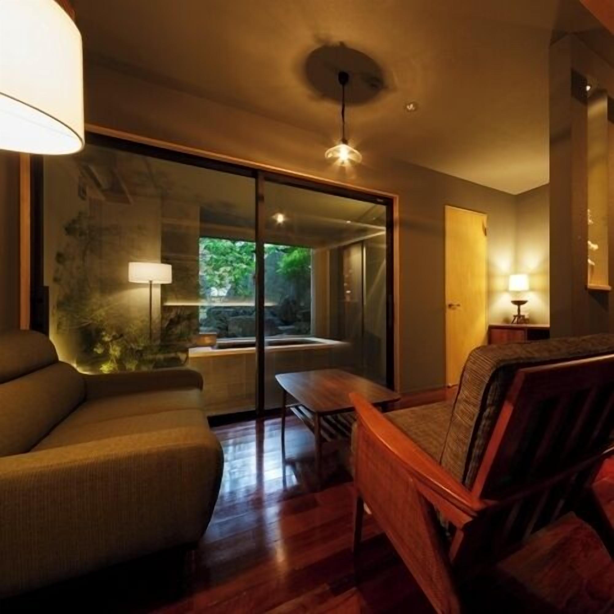 Una habitación moderna con un sofá, una mesa de madera y un ventanal de vidrio que da a un balcón.