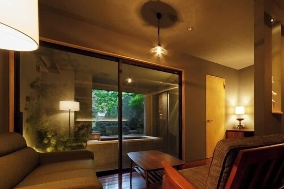 A modern room with a sofa, a wooden table, and a glass door leading to a balcony.