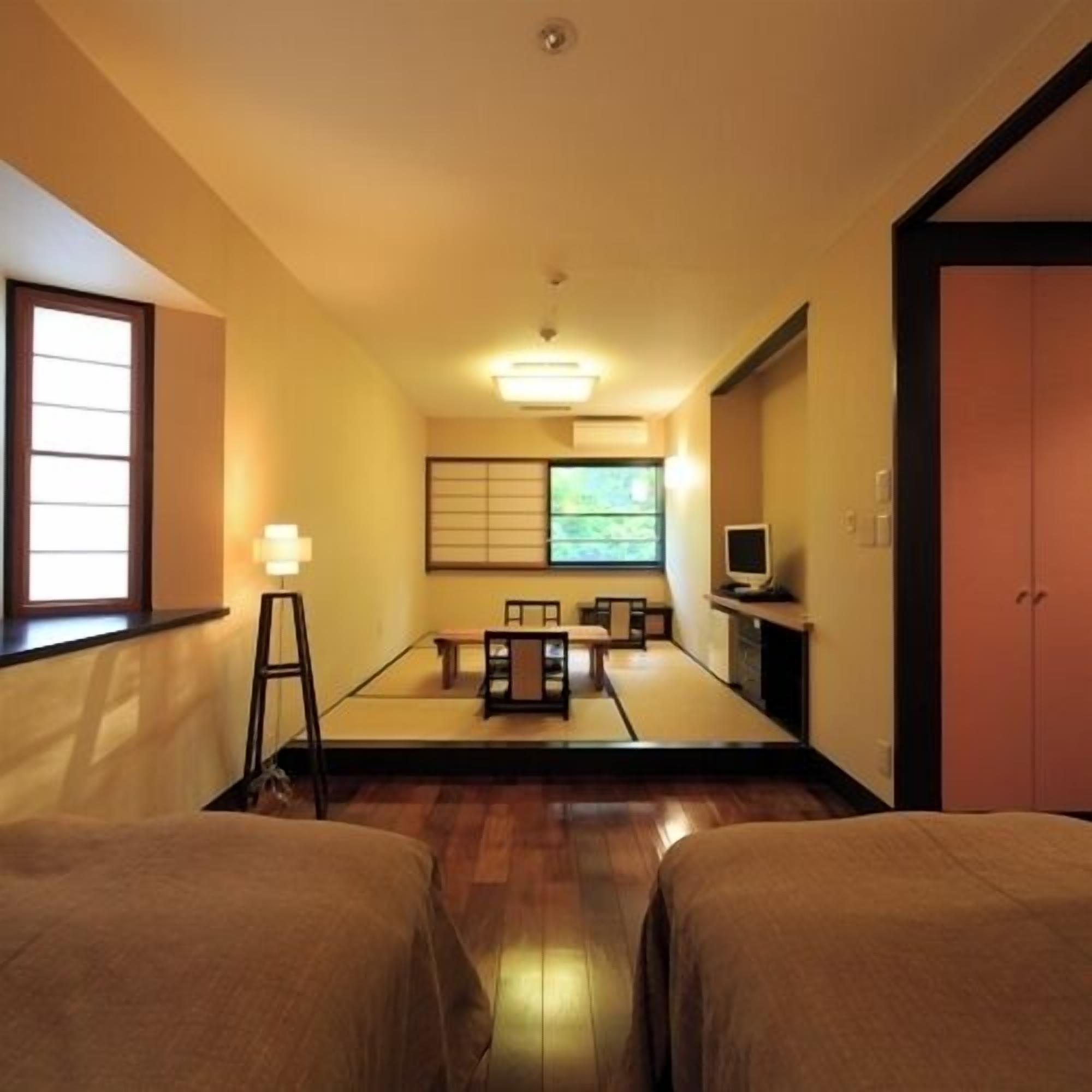 Una habitación japonesa tradicional con suelo de tatami, una mesa baja con cojines, un televisor y una puerta corredera.
