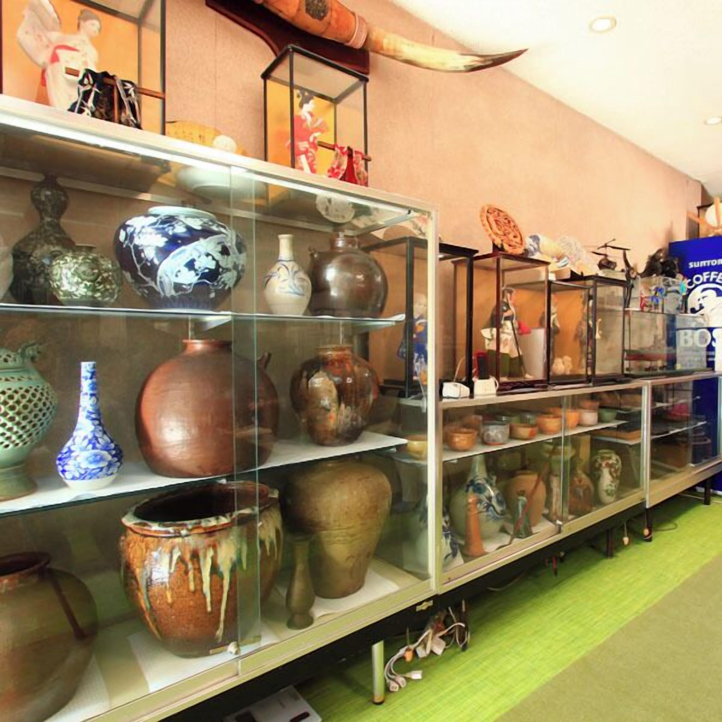 A display of various pottery items in a glass case, with a coffee machine in the background.