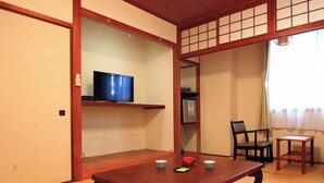 A traditional Japanese room with tatami flooring, a low wooden table, a television on a shelf, and a sliding door. - Tsushima no Kyodo wo Tanoshimu Ryokan Banshokaku (Tsushima)