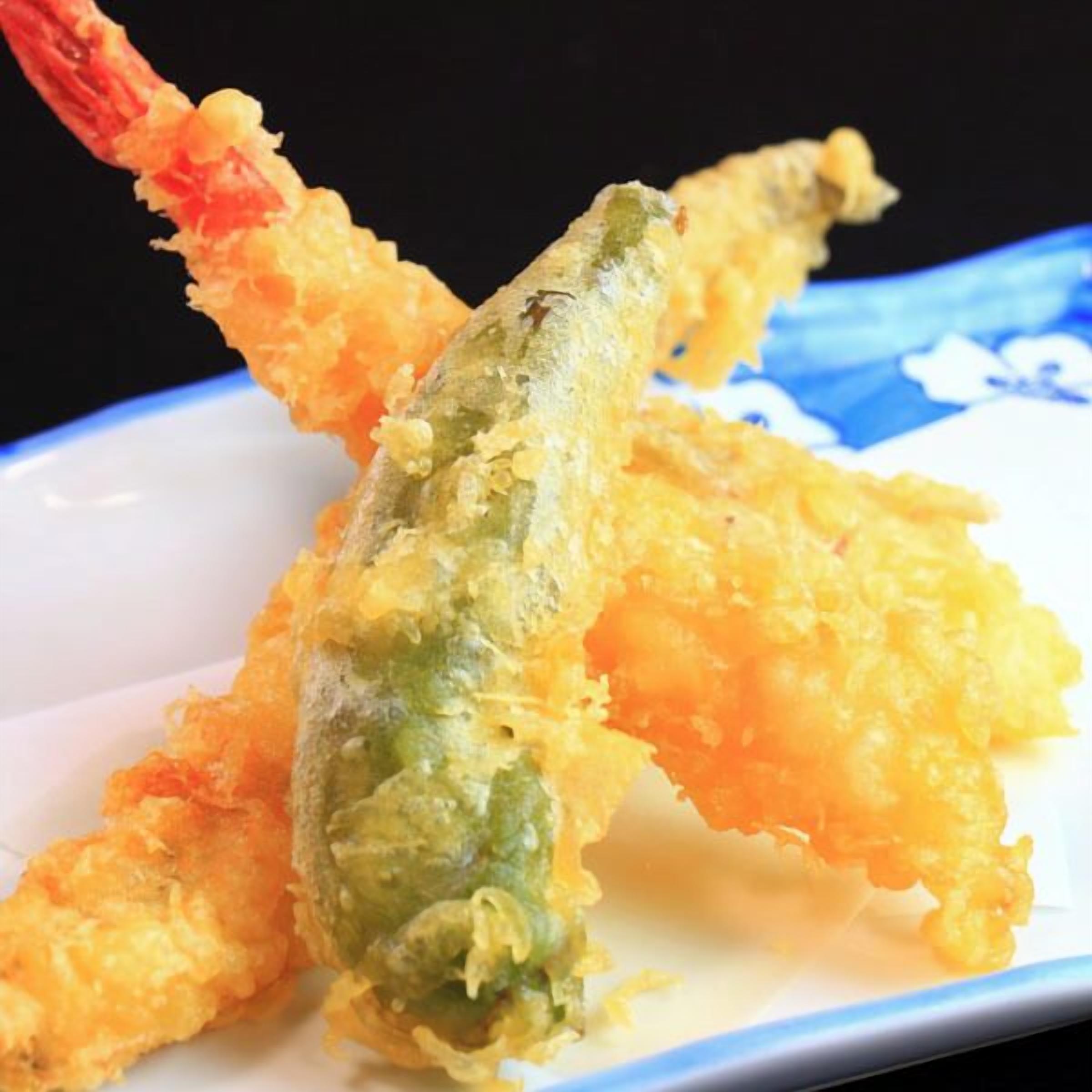 Un plato de camarones tempura con una capa crujiente de masa dorada.