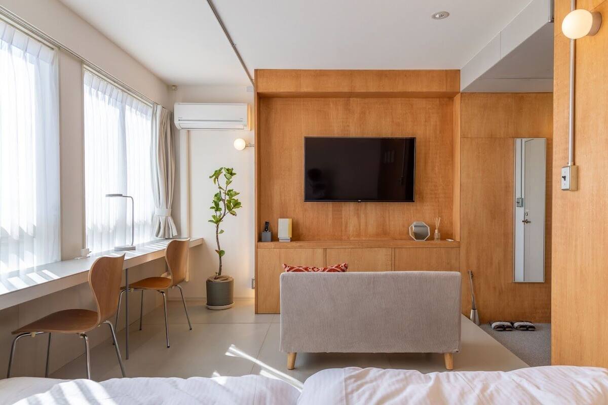 Een moderne hotelkamer met een grote televisie, een bureau, een stoel, een potplant en een bed.