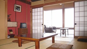 A traditional Japanese room with tatami flooring, a low wooden table, a television on a stand, and a sliding shoji screen door. - Rokko Ryokan (Suzu)