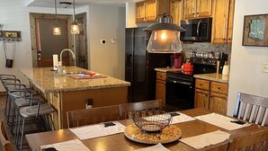A spacious kitchen with granite countertops, wooden cabinets, and stainless steel appliances.