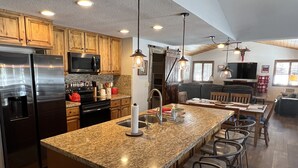 A spacious kitchen with granite countertops, wooden cabinets, and a central island with bar stools.
