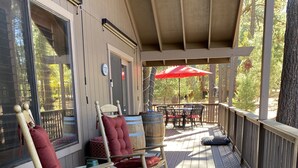A wooden deck with rocking chairs and a table, overlooking a garden.