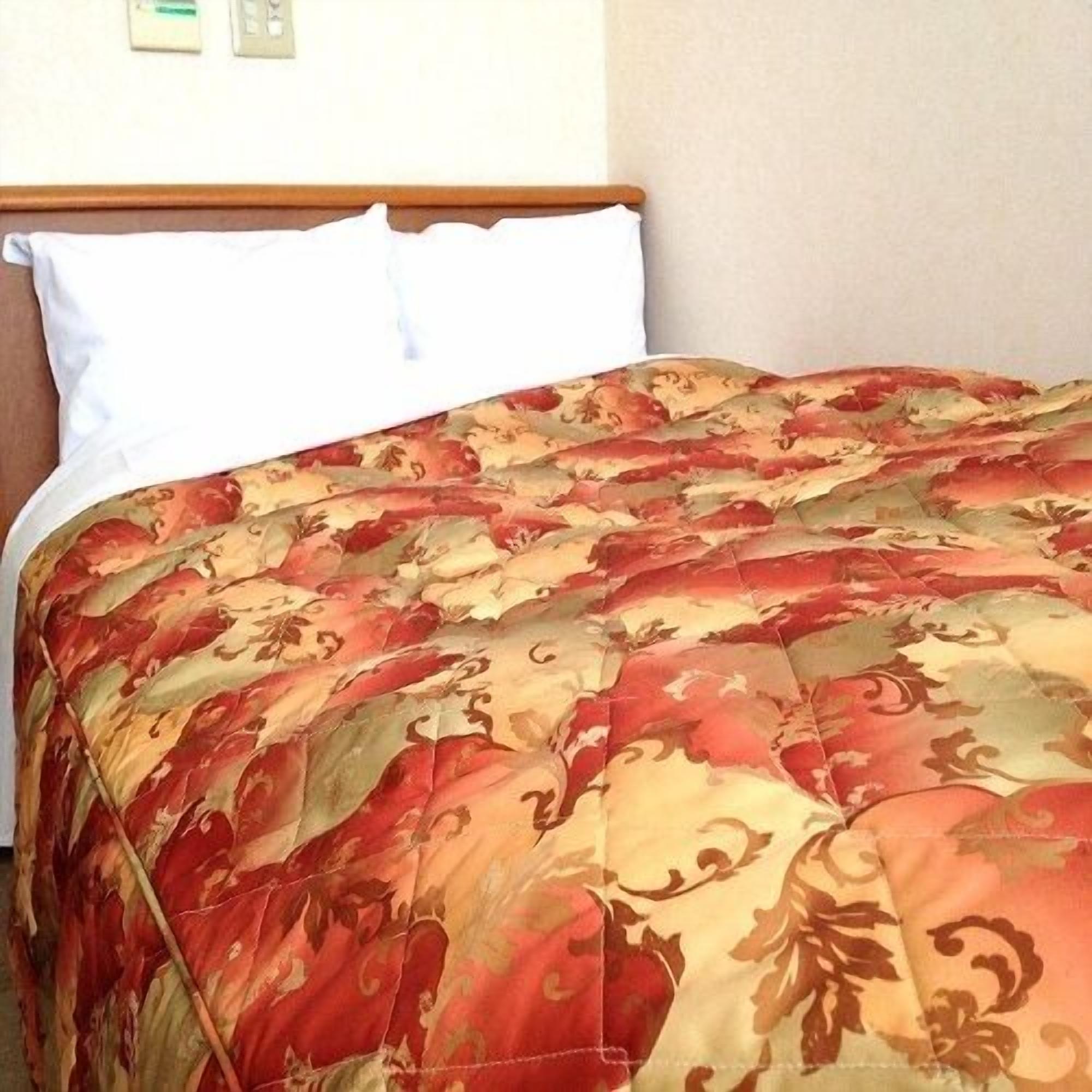 Een bed met een bloemenprint deken, witte kussens en een houten hoofdbord.