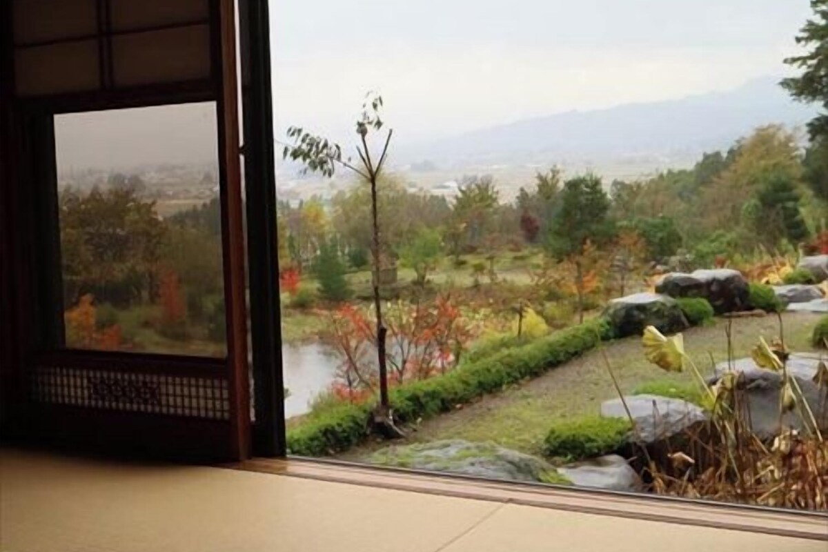 A traditional Japanese room with tatami flooring, a shoji screen, and a view of a landscaped garden.