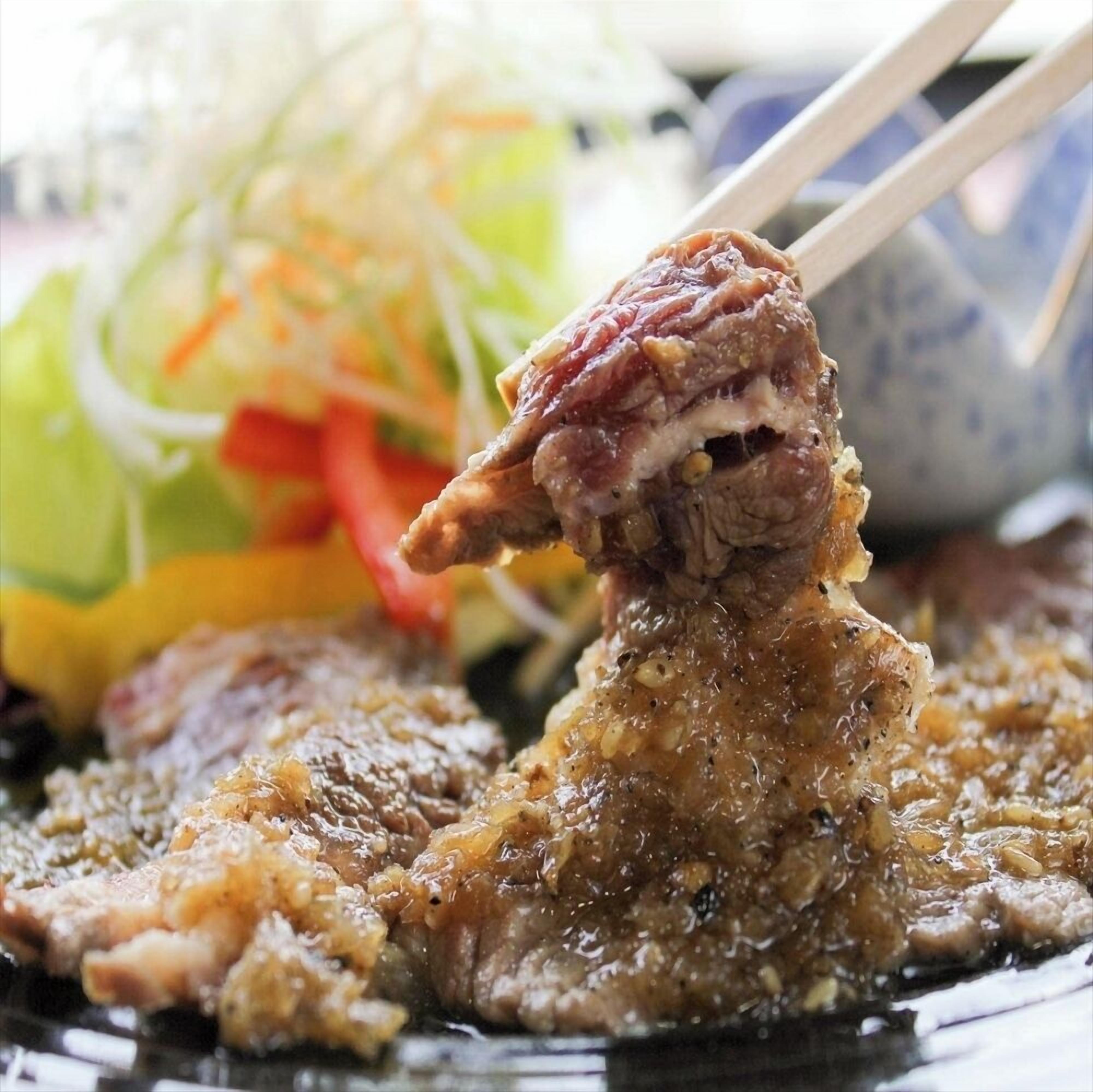 A close-up of a dish with meat and a side salad.