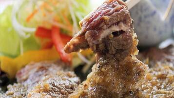 A close-up of a dish with meat and a side salad.