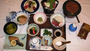 Ett urval av japanska rätter presenterade på ett fat, inklusive sushi, sashimi och en skål soppa.