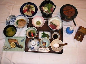 Variedad de platos japoneses dispuestos en una bandeja, incluyendo sushi, sashimi y un tazón de sopa.