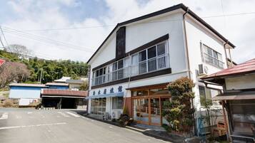 A two-story building with a large window and a balcony on the upper floor.