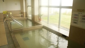An indoor swimming pool with clear glass walls, a small stool, and a potted plant. - Green Stay Nagaura (Suooshima)