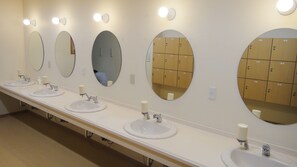 A row of sinks with mirrors and storage lockers in a public restroom.