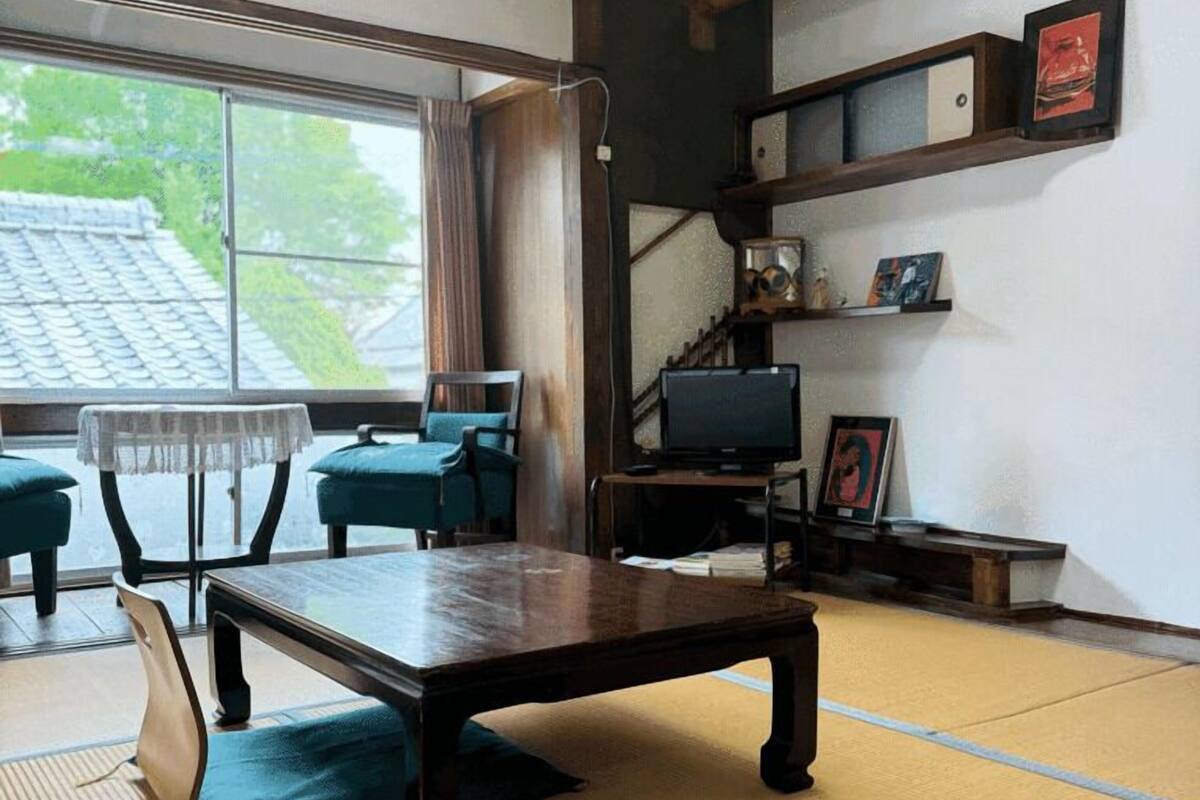 A traditional Japanese room with tatami flooring, a low table, and a television.
