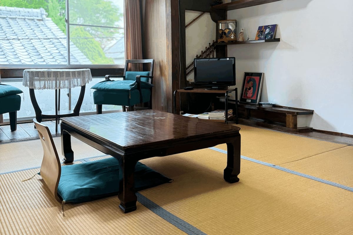 A traditional Japanese room with tatami flooring, a low table, and a television.