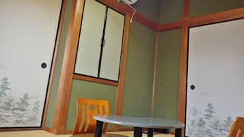 A room with a traditional Japanese-style sliding door, a small round table, and a single orange chair.
