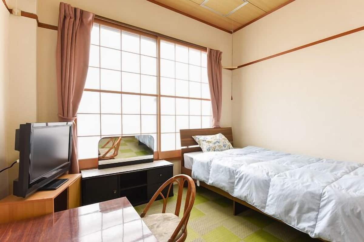 A bedroom with a bed, a television, a desk, and a chair.
