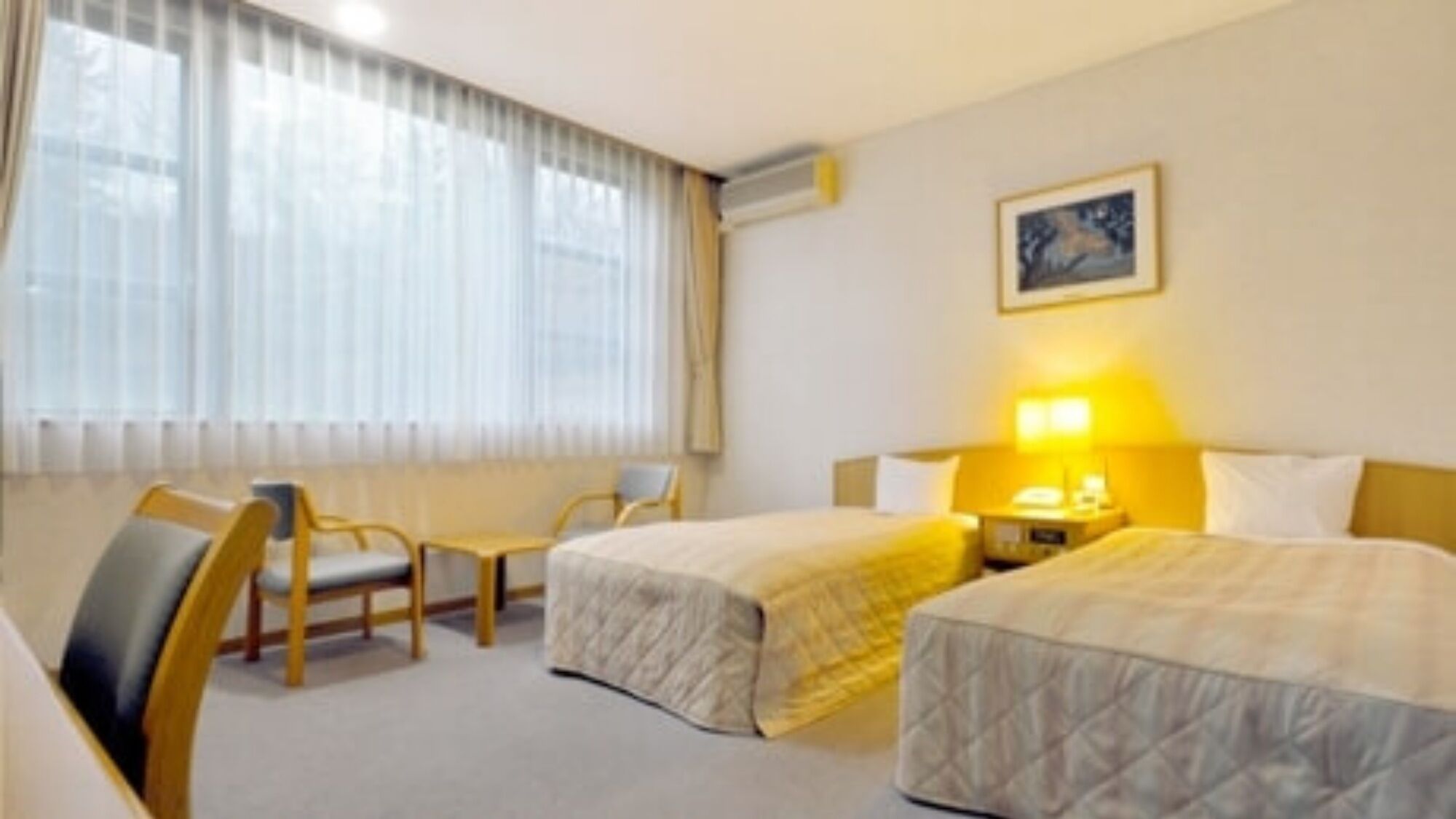Habitación de hotel con dos camas, un escritorio, una silla y un ventanal con cortinas.