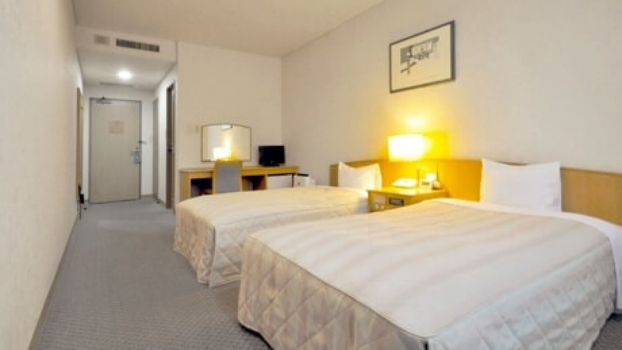 Habitación de hotel con dos camas, un escritorio, una silla y un televisor.