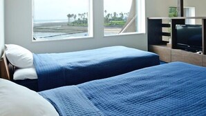 Ein Schlafzimmer mit zwei Betten, großen Fenstern, einem Fernseher und einer Holzbalkendecke.