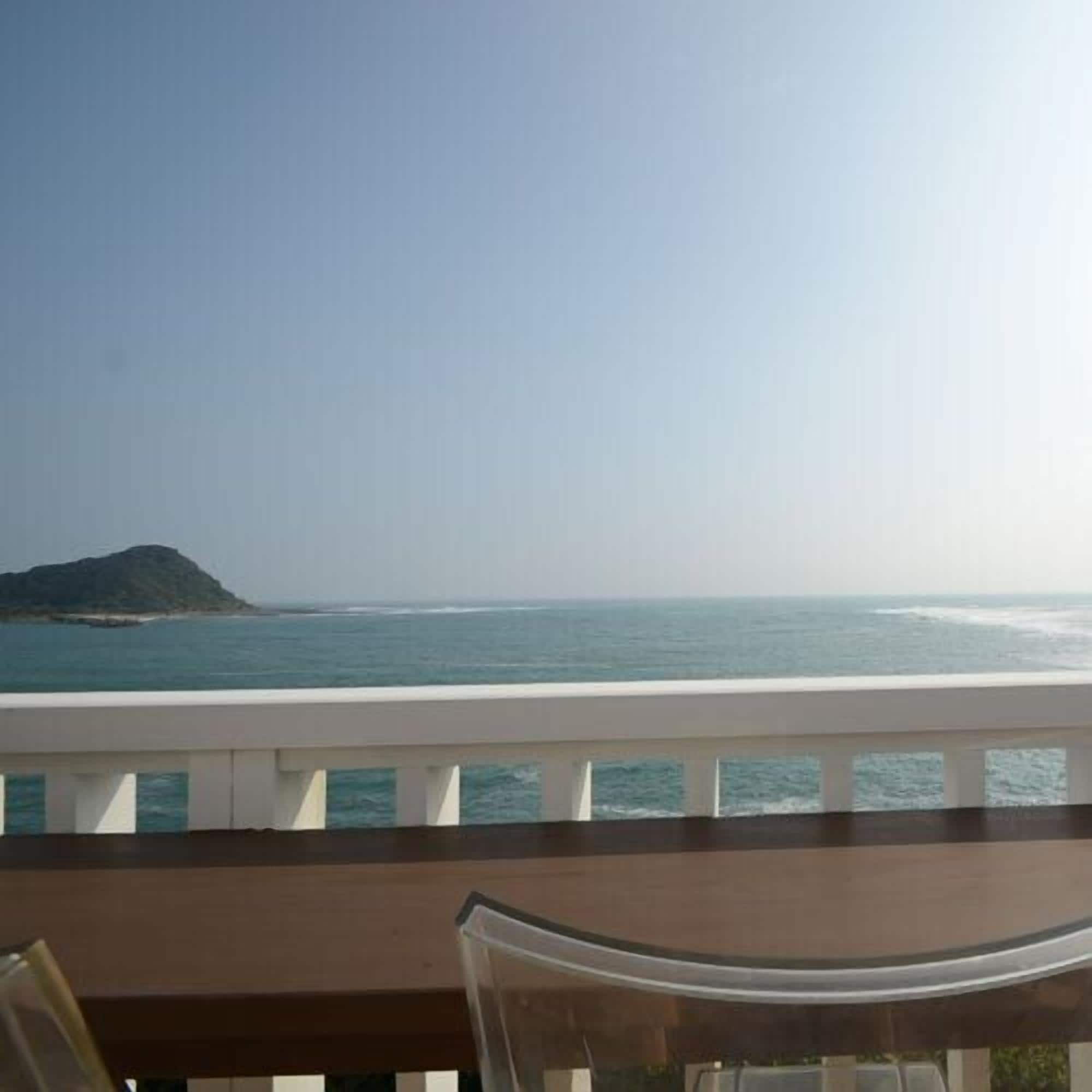 A balcony with a view of the sea and a distant island.