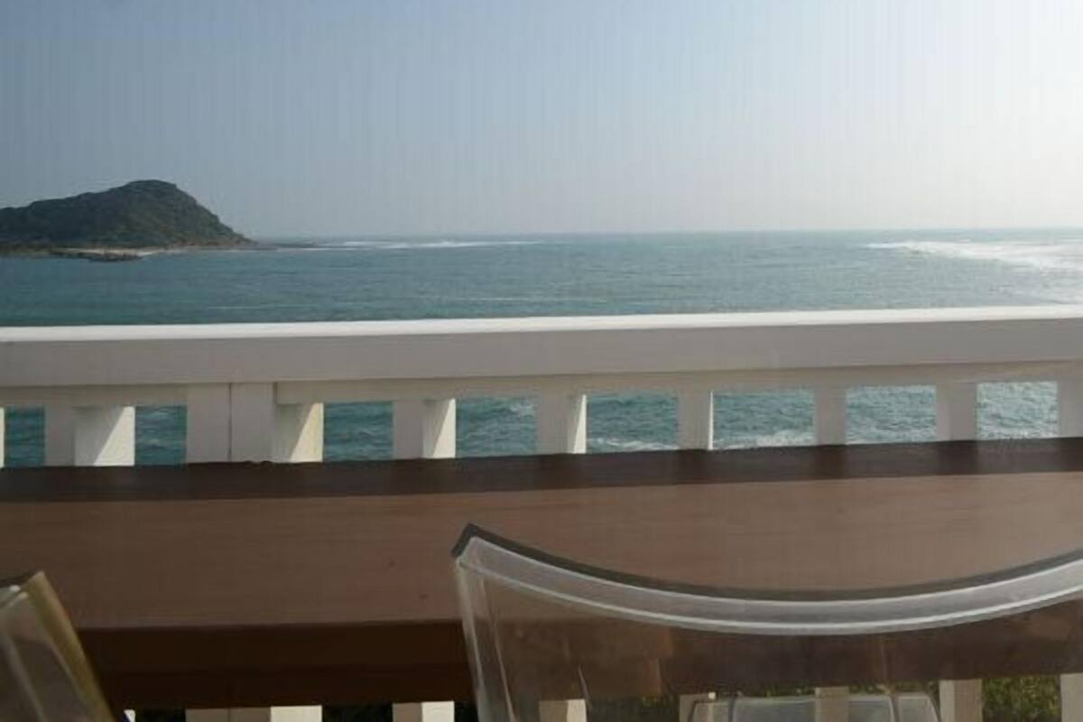 A balcony with a view of the sea and a distant island.