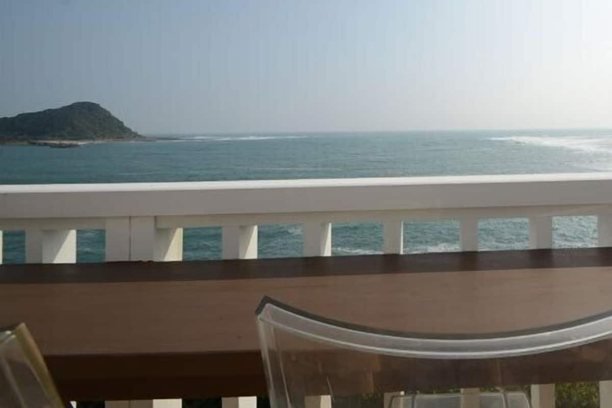 A balcony with a view of the sea and a distant island.