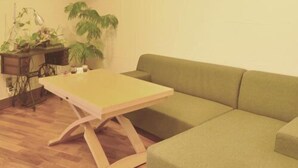 A room with a green sofa, a wooden table, and a sewing machine. - Epurontei (Miyazaki)