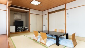 Una habitación tradicional japonesa con suelo de tatami, una mesa baja y un televisor.