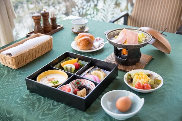 A table set with a variety of food items, including a hot pot, sushi, and a bowl of eggs.