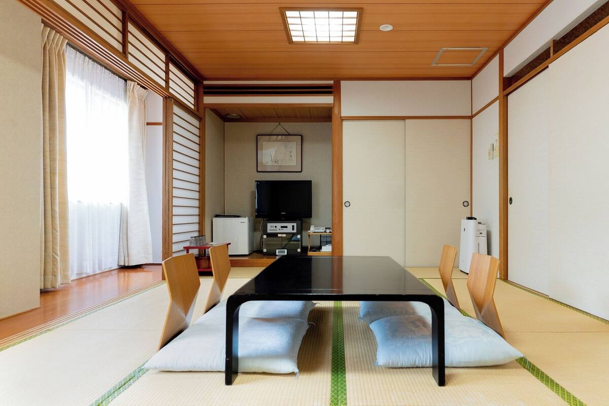 Une pièce de style japonais traditionnel, avec un sol recouvert de tatamis, une table basse et des portes coulissantes.