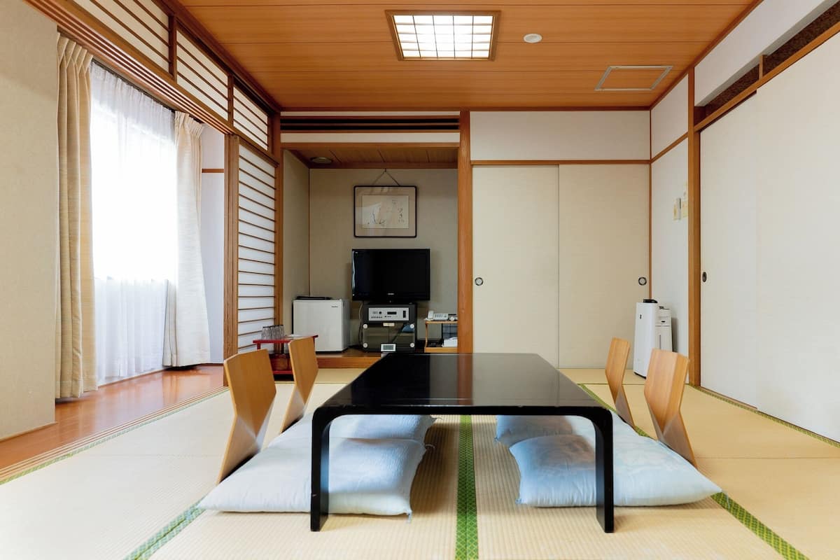 Una habitación tradicional japonesa con suelo de tatami, una mesa baja y puertas correderas.
