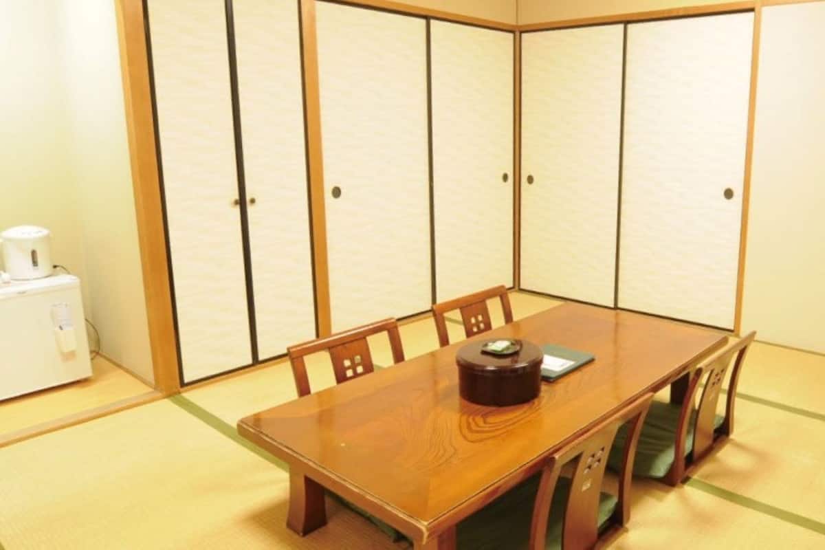 A traditional Japanese-style room with tatami flooring, a wooden table, and shoji screens.