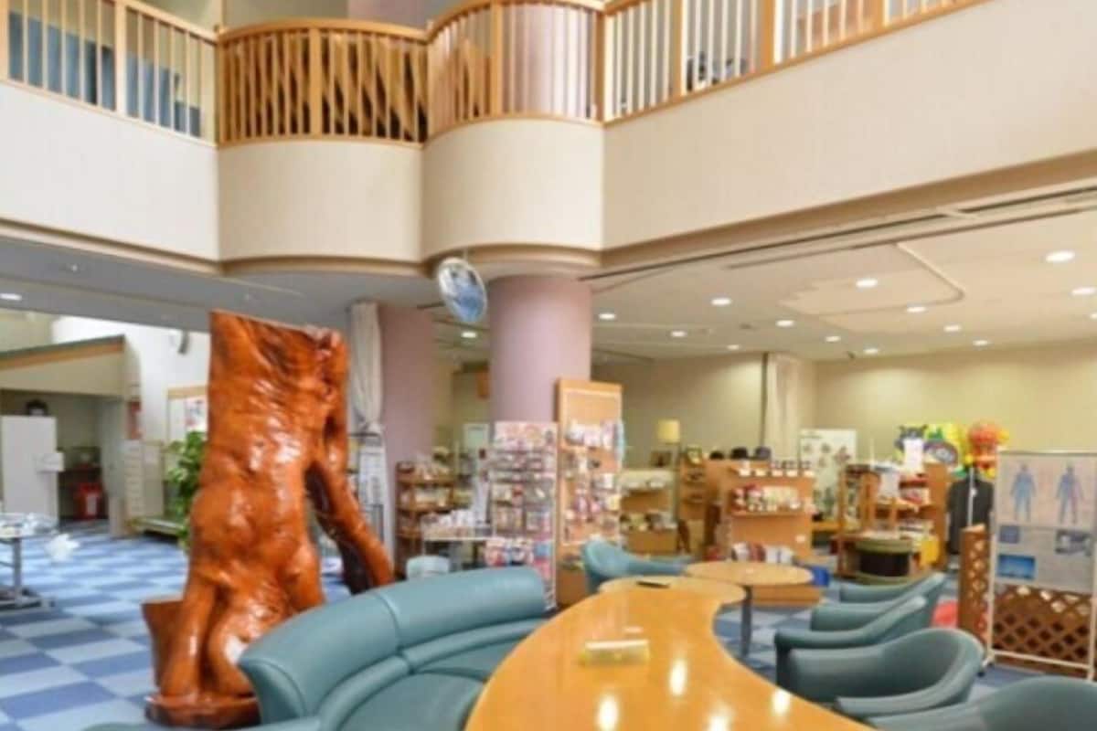A hotel lobby with a central seating area, a wooden staircase, and a large wooden sculpture.