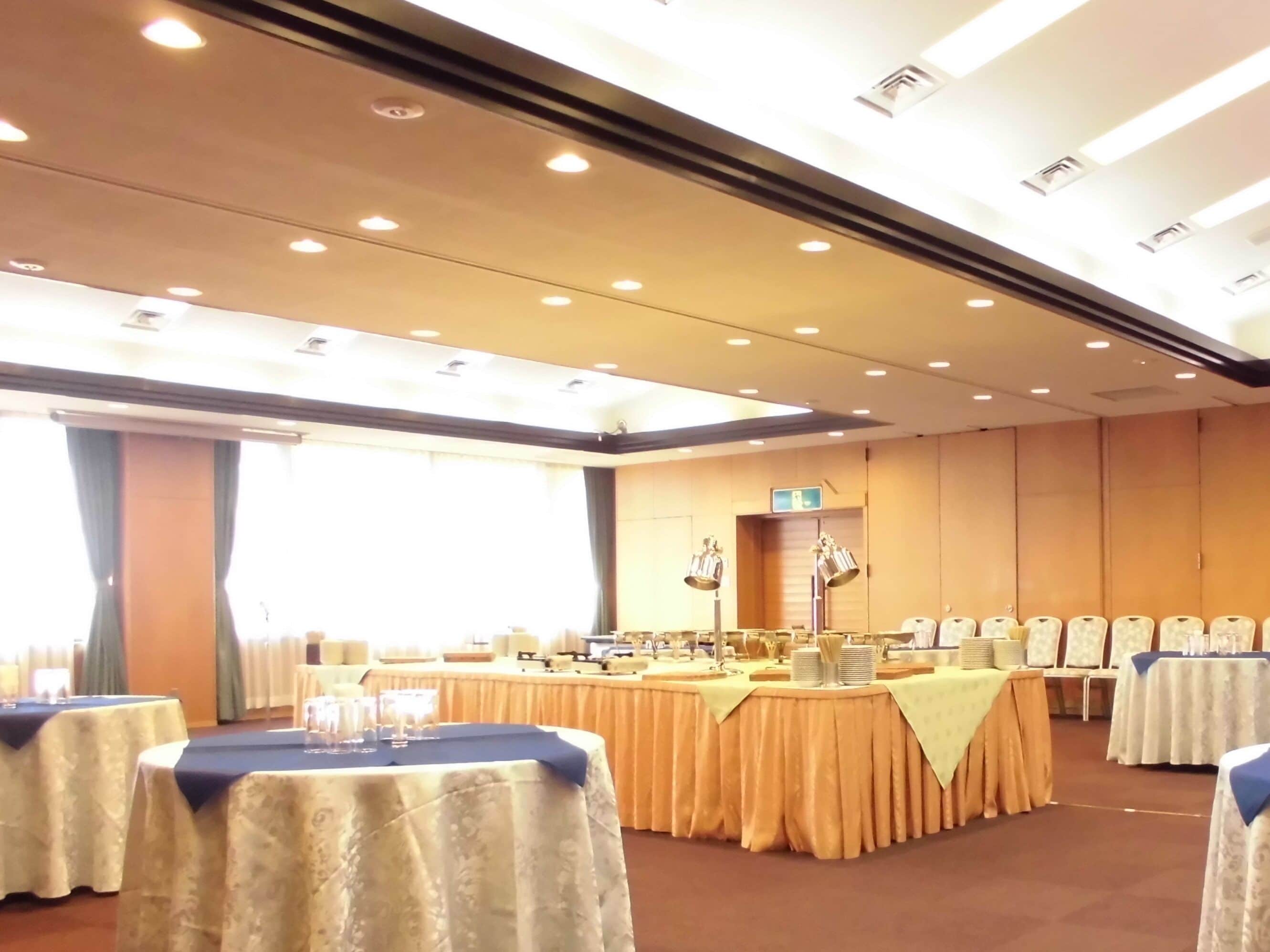 A conference room with tables set for a meeting, a large window, and a ceiling with recessed lighting.