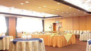 Une salle de conférence avec des tables disposées pour une réunion, une grande fenêtre et un plafond doté d’un éclairage encastré.