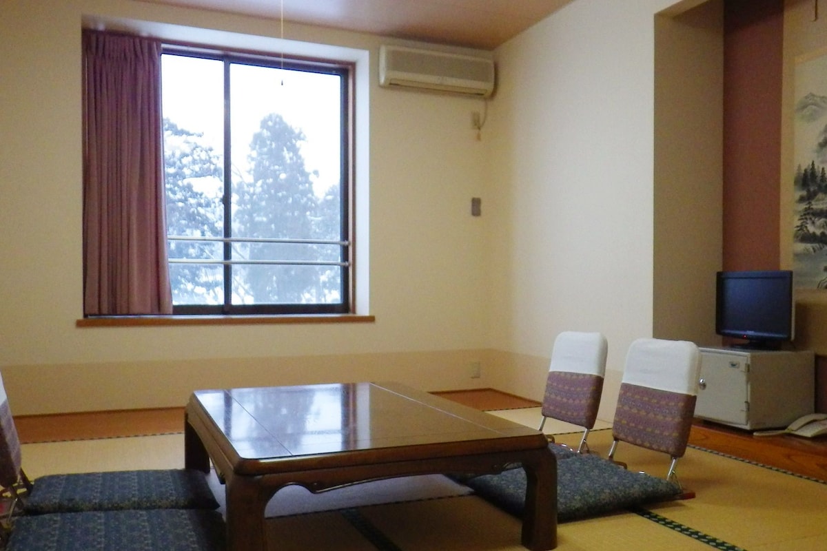Una habitación con una mesa de madera, dos sillas, un televisor y un cuadro en la pared.