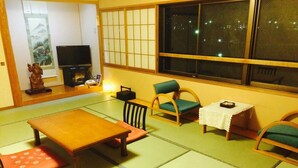 A tatami mat room with a low table, chairs, a television, and a decorative statue. - Tokurakamiyamada Onsen Yu No Yado Fukujuso (Chikuma)