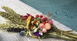 A bouquet of flowers placed on a tiled surface near a pool. - Oishii Gakko (Hokuto)