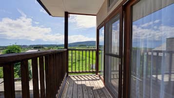 Un balcón de madera con vistas a un paisaje verde y montañas lejanas.