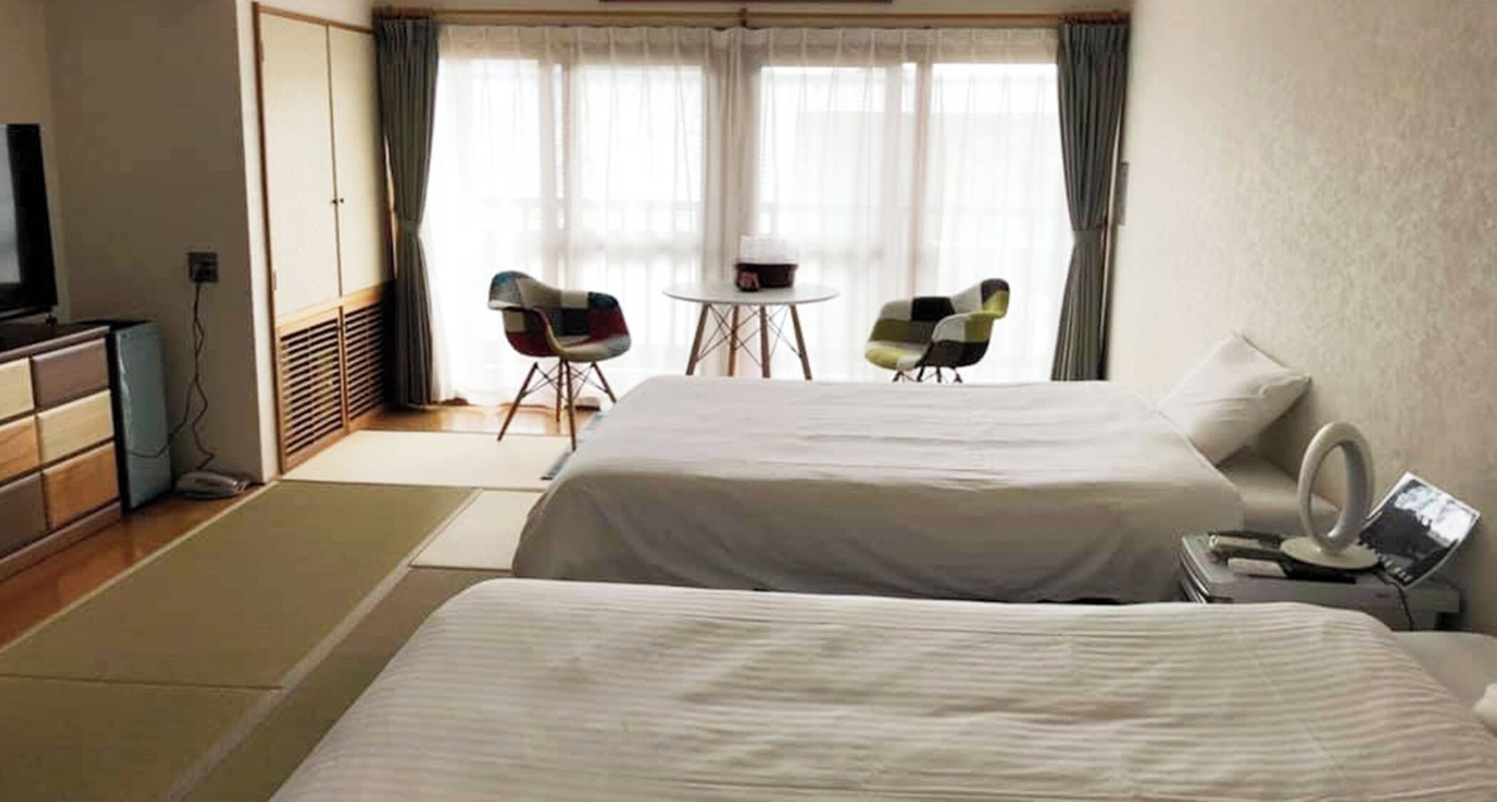 Une chambre d’hôtel avec deux lits, un bureau, une chaise et un téléviseur.
