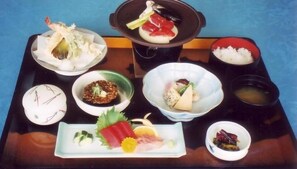 A tray with various Japanese dishes including sashimi, rice, and soup. - Hotel Tamai (Aki)