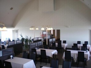 A restaurant with multiple tables and chairs, a staircase, and a plant. - Hotel Tamai (Aki)