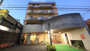 A multi-story building with a ground-level entrance, a visible storefront, and a balcony on the upper floors. - Okumusashi Ryokan (Hanno)