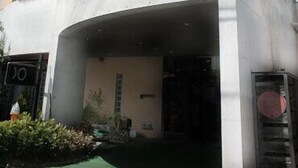 A multi-story building with a curved facade, balconies, and a visible entrance. - Okumusashi Ryokan (Hanno)